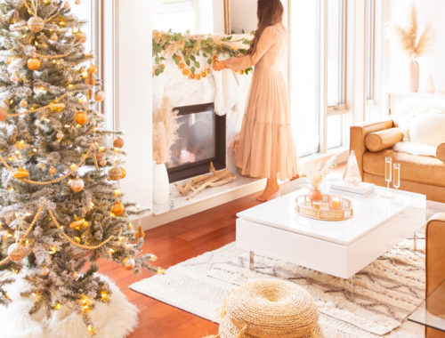 Mid Century Meets Boho Holiday Decor | Brunette woman wearing a taupe chiffon maxi dress hanging stockings in a bright and airy bohemian living room decorating for Christmas | Flocked Christmas Tree with Wood Garland, Metallic and Wood Ornaments | Bohemian Holiday Home Tour 2020 | Boho Chic Christmas Decor | DIY boho dried orange garland | Glam neutral holiday decor | Pampas Grass holiday decor | Pampas Grass Garland | Boho Christmas Tree | Canadian Tire CANVAS Ornaments // JustineCelina.com
