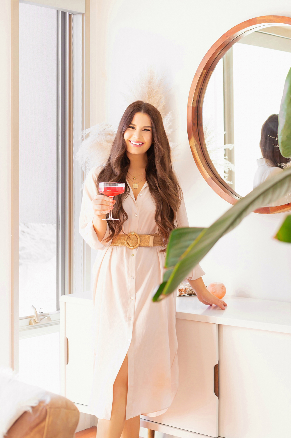 Brunette woman holding a champagne coupe of watermelon kombucha in a bright and airy living room | Calgary Lifestyle Blogger // JustineCelina.com