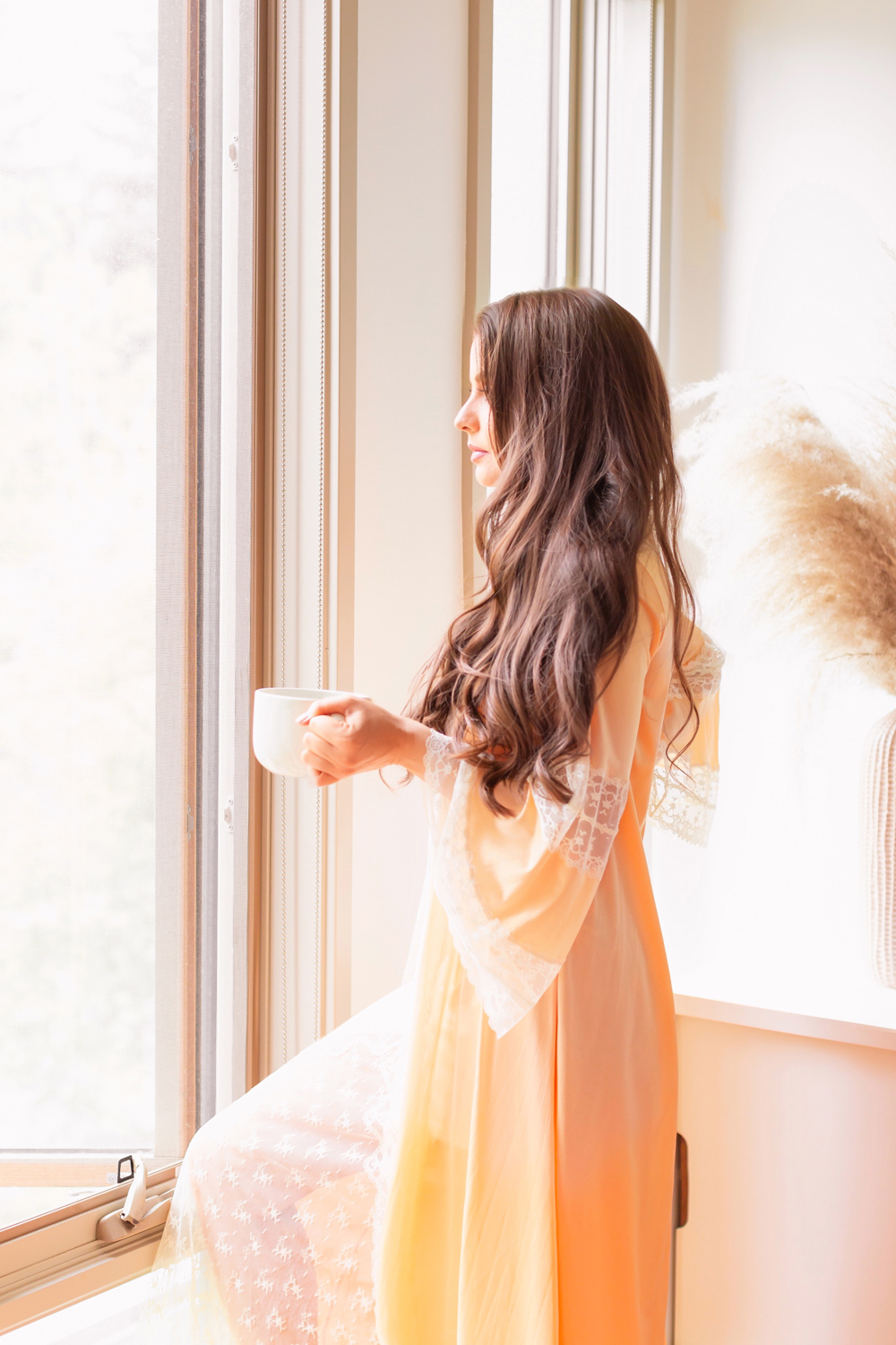 Brunette woman wearing a vintage dressing gown holding a mug of tea in bright and airy boho living room | Calgary Lifestyle Blogger // JustineCelina.com