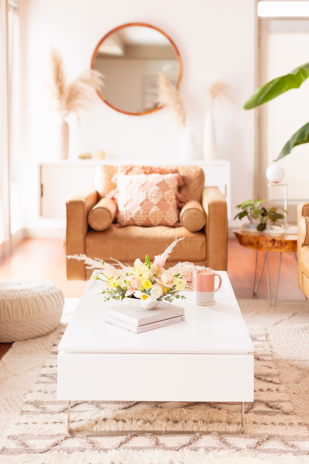 A Pastel Easter Flower Arrangement featuring pampas grass on white coffee table with a pink mug in bright and airy mid century meets boho living room | Calgary Lifestyle Blogger // JustineCelina.com