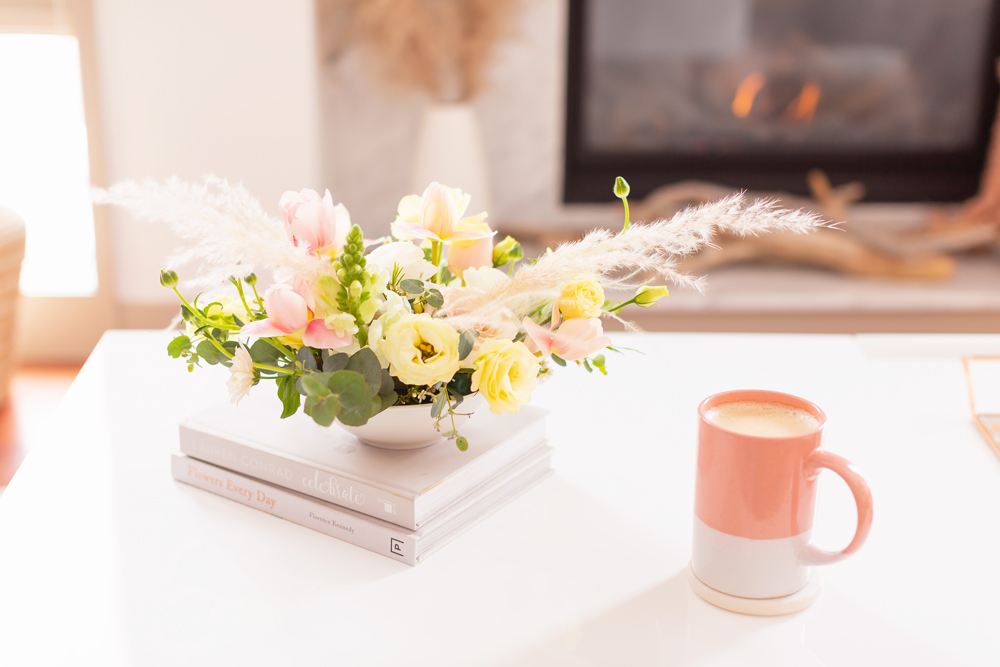 An easter flower arrangement with pampas grass on white coffee table with a pink mug in front of a white marble fireplace | Calgary Lifestyle Blogger // JustineCelina.com