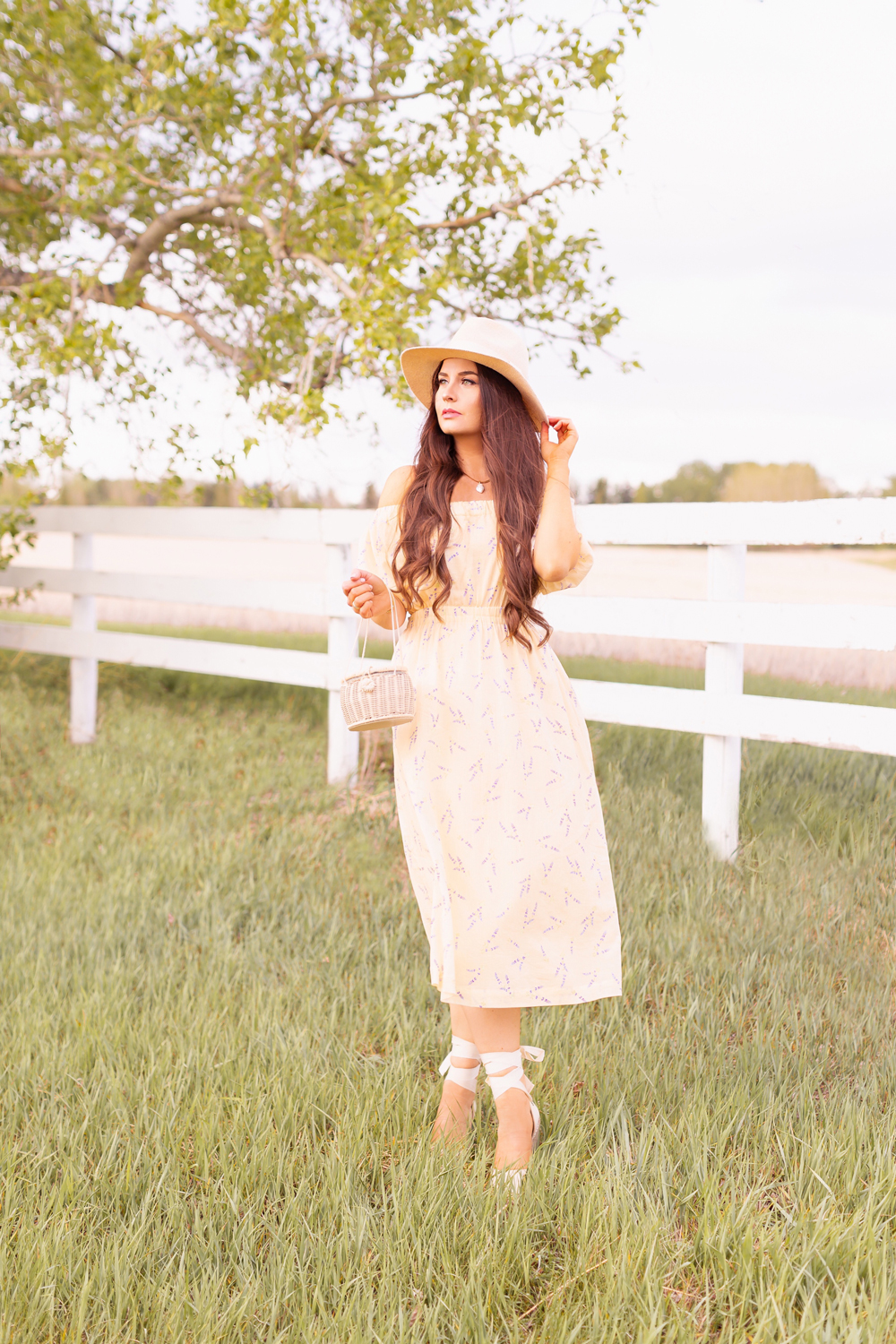 H&M Wildflower Collection Review | Brunette woman wearing a H&M A Meadow of Wildflowers Collection Off-the-shoulder Dress with a woven fedora, straw basket bag and cream espadrilles on an acreage with a white fence | H&M Wildflower Collection Canada | H&M Wildflower Collection Canada | Spring/Summer 2021 Trends | The Best Cotton Dresses 2021 | The Best H&M Dresses Summer 2021 | Alberta Wildflower Field | Cottage Core Fashion | Calgary Creative Lifestyle & Fashion Blogger // JustineCelina.com