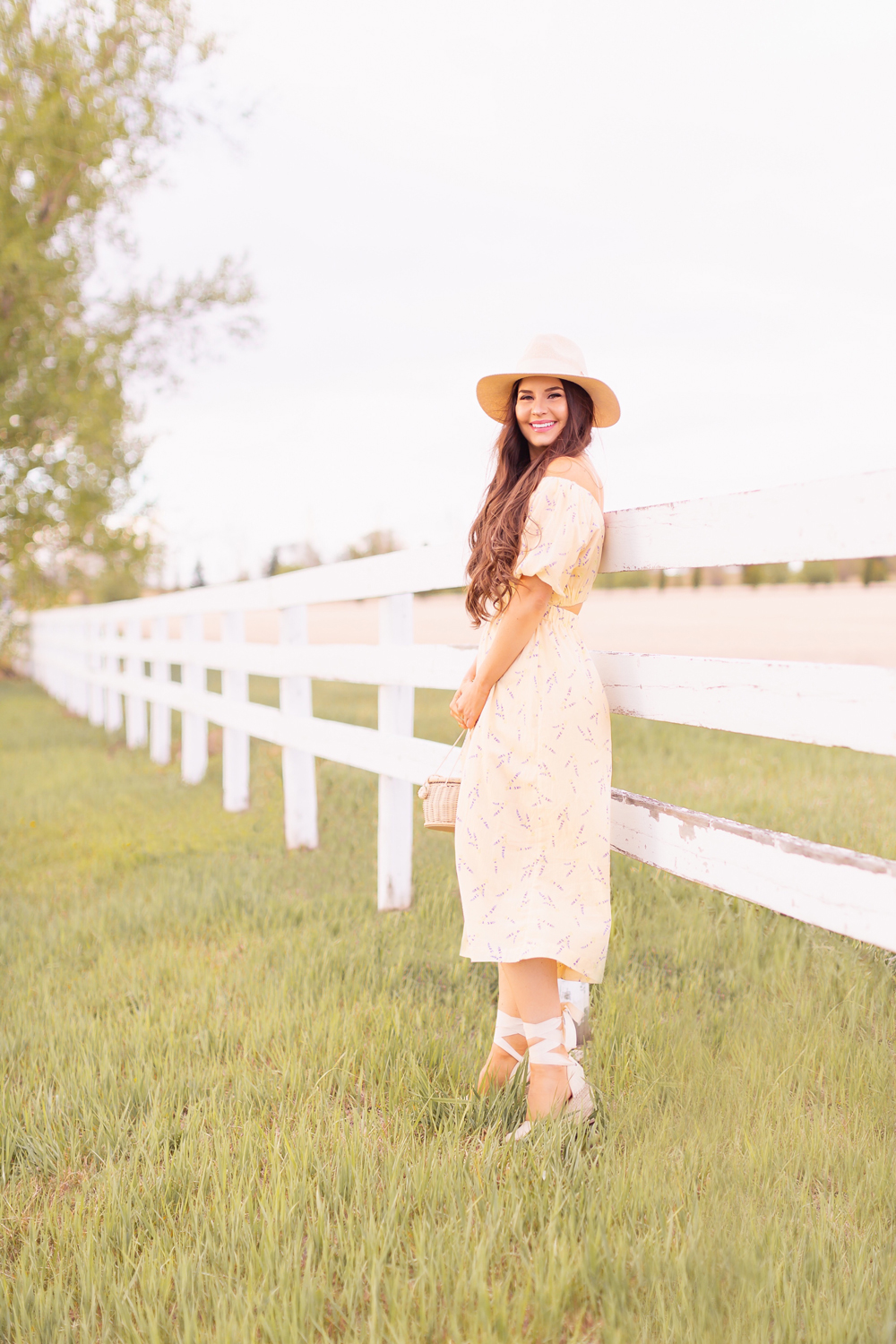H&M Wildflower Collection Review | Brunette woman wearing a H&M A Meadow of Wildflowers Collection Off-the-shoulder Dress with a woven fedora, straw basket bag and cream espadrilles on an acreage with a white fence | H&M Wildflower Collection Canada | H&M Wildflower Collection Canada | Spring/Summer 2021 Trends | The Best Cotton Dresses 2021 | The Best H&M Dresses Summer 2021 | Alberta Wildflower Field | Cottage Core Fashion | Calgary Creative Lifestyle & Fashion Blogger // JustineCelina.com