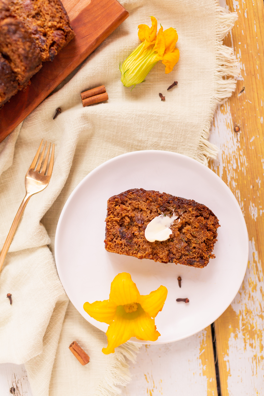 Cinnamon Raisin Zucchini Bread {Dairy Free, Gluten Free, Refined Sugar Free} | Freshly baked, sliced Zucchini Bread on a wooden serving board surrounded by squash blossoms, cinnamon sticks and cloves | Moist Zucchini Bread Recipe | Easy Cinnamon Raisin Loaf | Best Baking Recipes for Overgrown Garden Zucchini | Zucchini Bread Cake | Healthy Cinnamon Zucchini Bread | What to do with large zucchini | Zucchini Bread with Crispy Top | Calgary Plant Based Food Blogger // JustineCelina.com